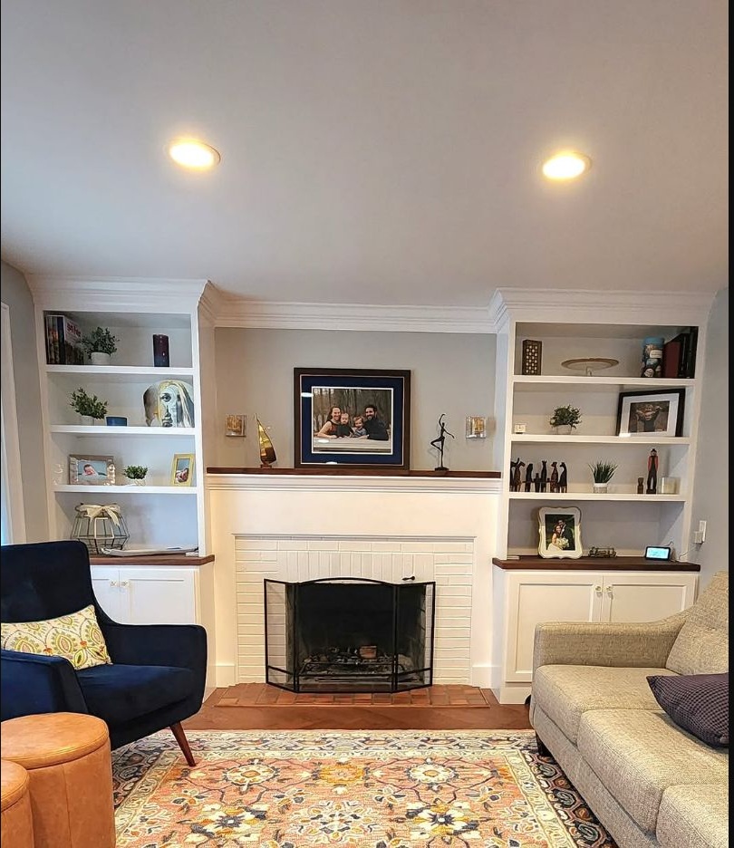 White fireplace surround with custom cabinetry and dark wood shelving